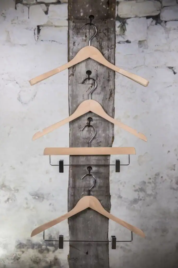 Holzkleiderbügel an rustikalem Holzständer, ideal für nachhaltige Garderoben.